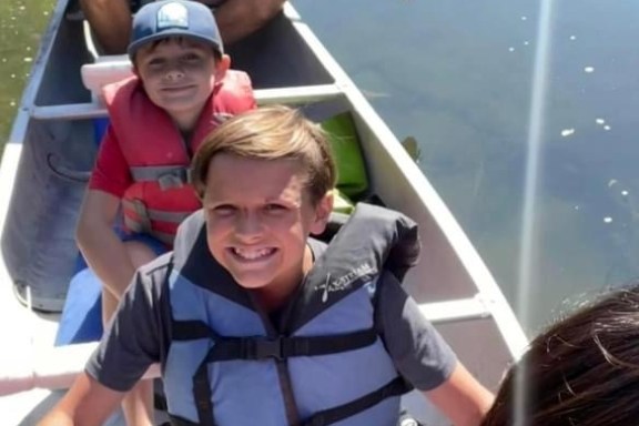 a boy and a girl sitting on a boat in the water